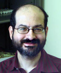 a picture of a bearded man with brown glasses, balding on top, brown beard and brown hair